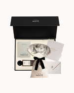 Atelier Noitē gift set with eye mask, pouch, and cards in a black box on a white background