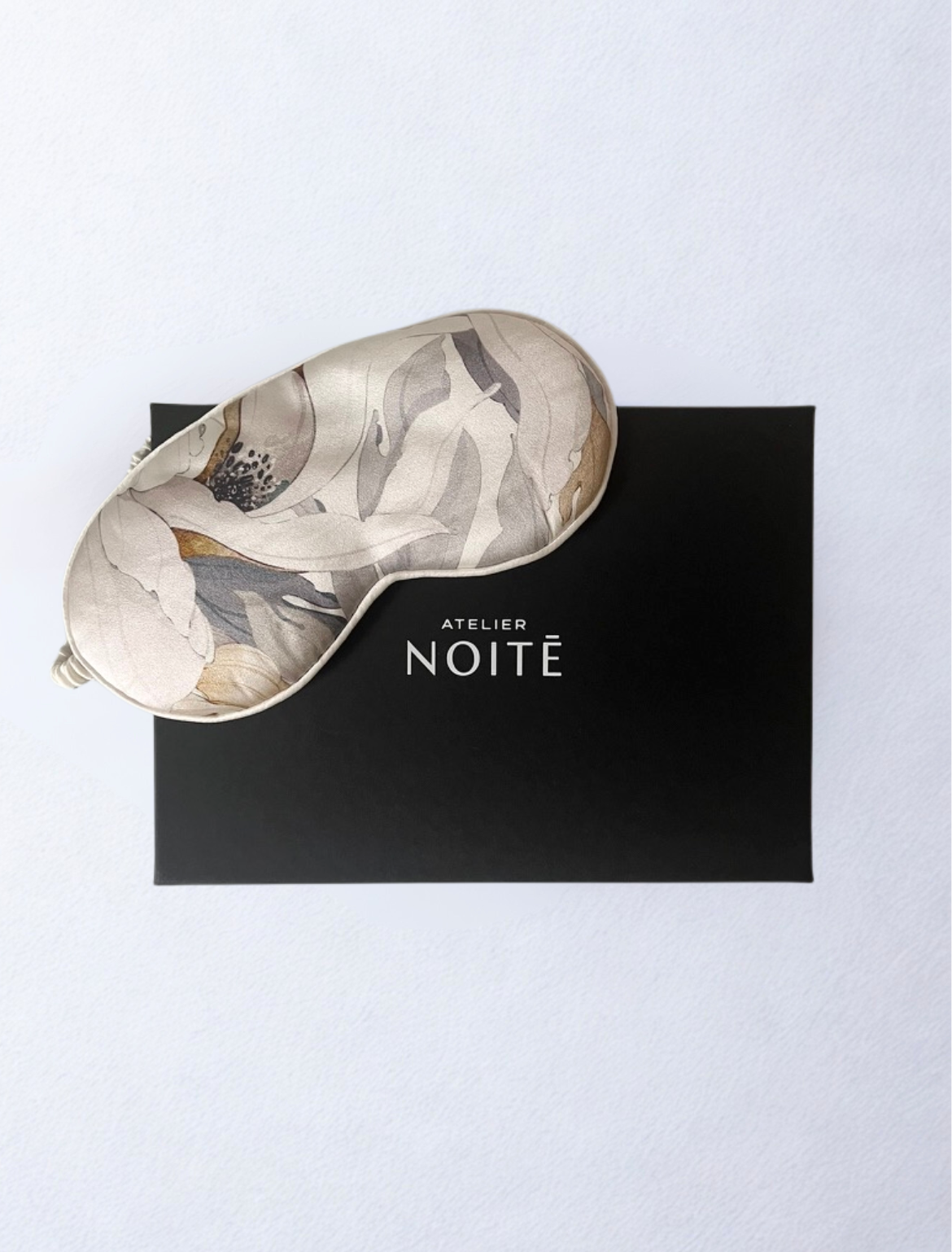 White silk mask with floral print with a black gift box