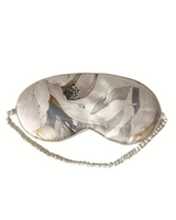 Sleep mask with abstract leaf pattern on a white background